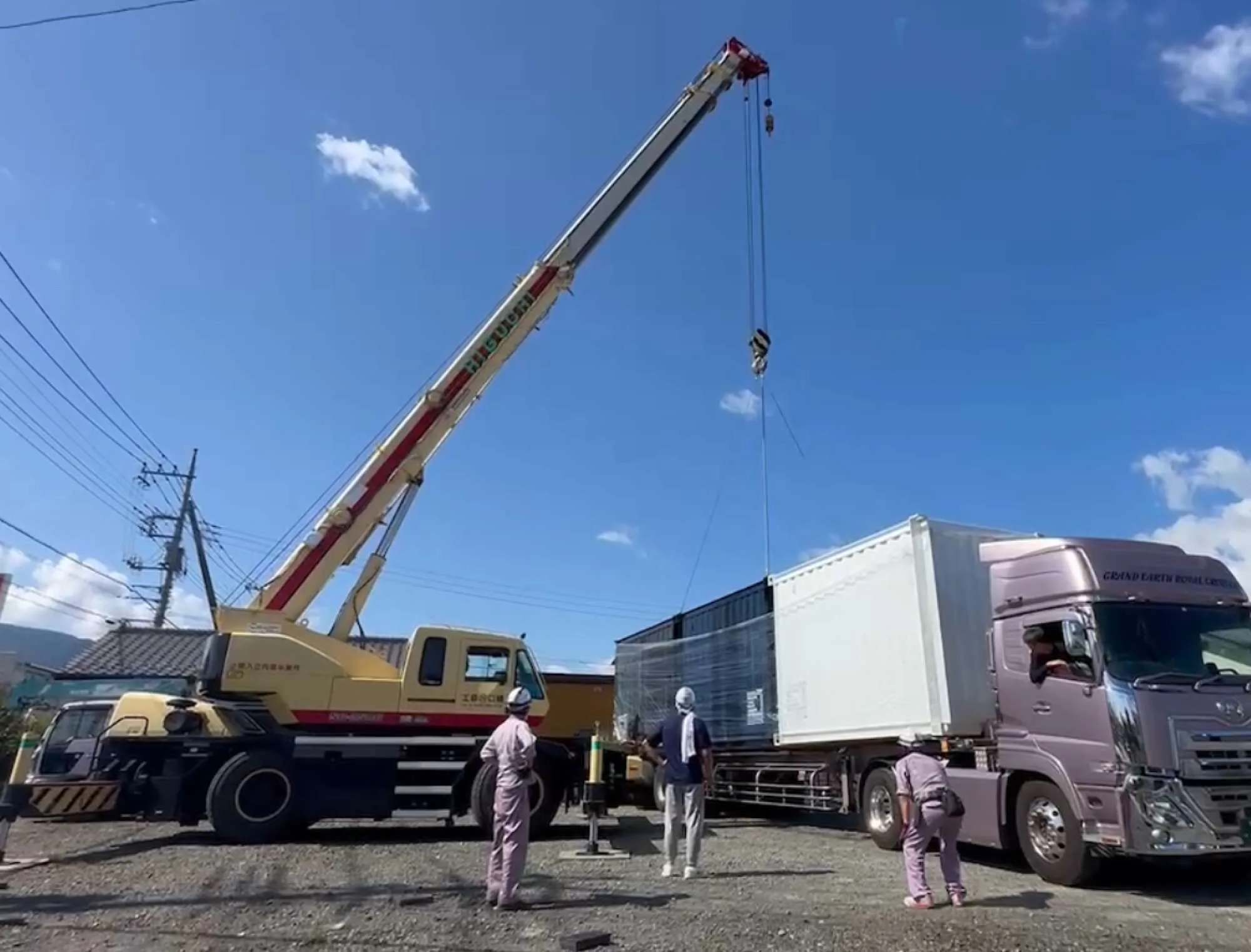 トラックからクレーンで展示用コンテナを吊り上げる工程